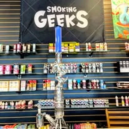 A tall hookah on the shelf beneath the Smoking Geeks banner